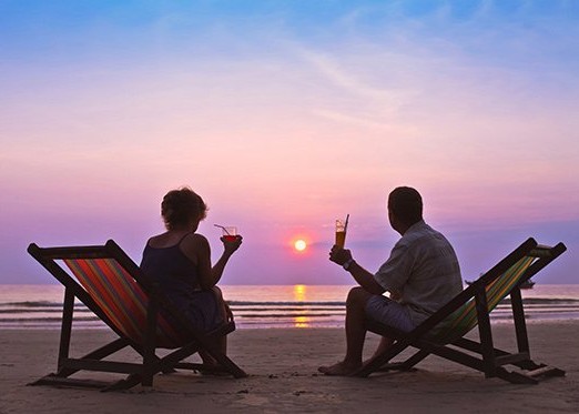 Mann und Frau mit Drink beim Sonnenuntergang