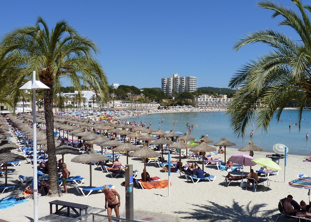 Sandstrand mit Sonnenschirmen und Palmen